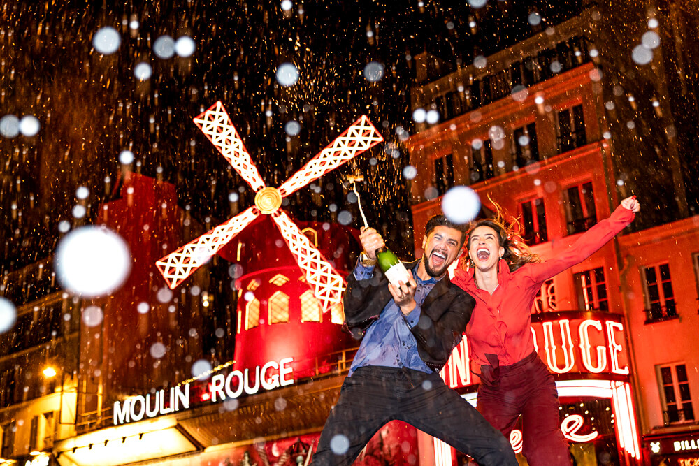 Happy couple popping Champagne in front of Moulin Rouge, Paris photoshoot