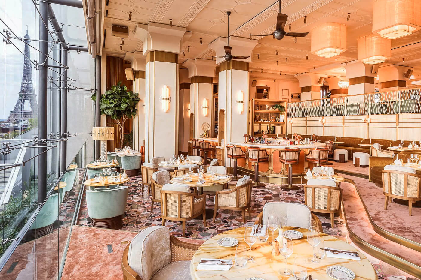 Gigi Rigolatto's elegant dining room featuring marble tables, floor-to-ceiling windows with Eiffel Tower views, and stylish bar area