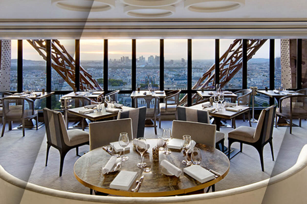 Le Jules Verne's elegant dining room featuring floor-to-ceiling windows with dramatic Eiffel Tower ironwork as part of the restaurant's interior
