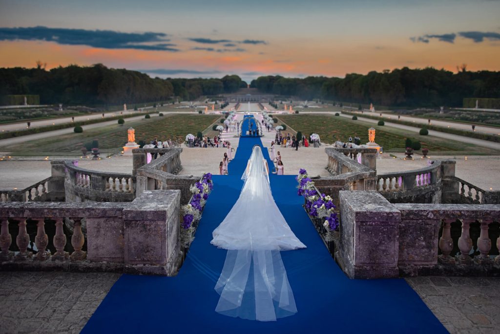 Luxury Paris wedding photography: bride in Dior haute couture descending Château de Vaux-le-Vicomte's grand staircase, captured for her prestigious French castle wedding