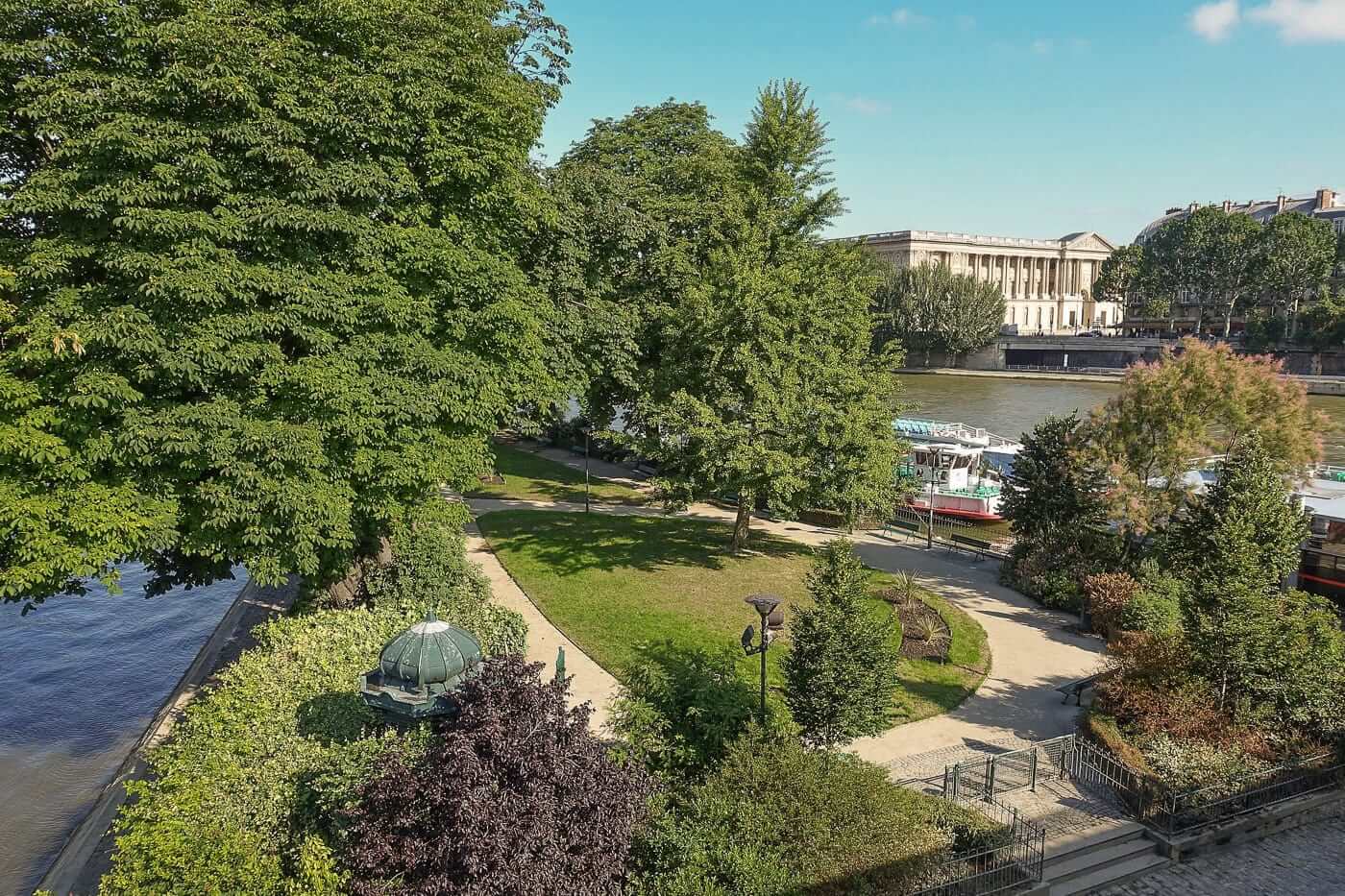 Square du Vert-Galant Paris - lush green island garden surrounded by Seine River with bridge and Louvre views