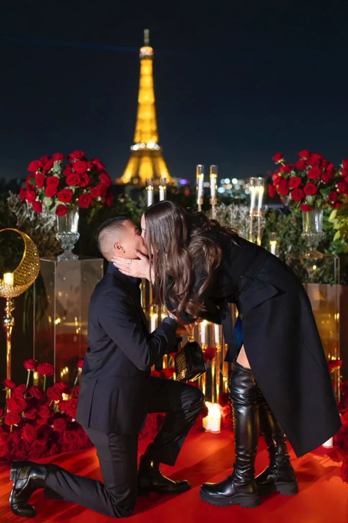 Man proposing on red carpet with roses and candles at Peninsula Hotel Paris with Eiffel Tower view