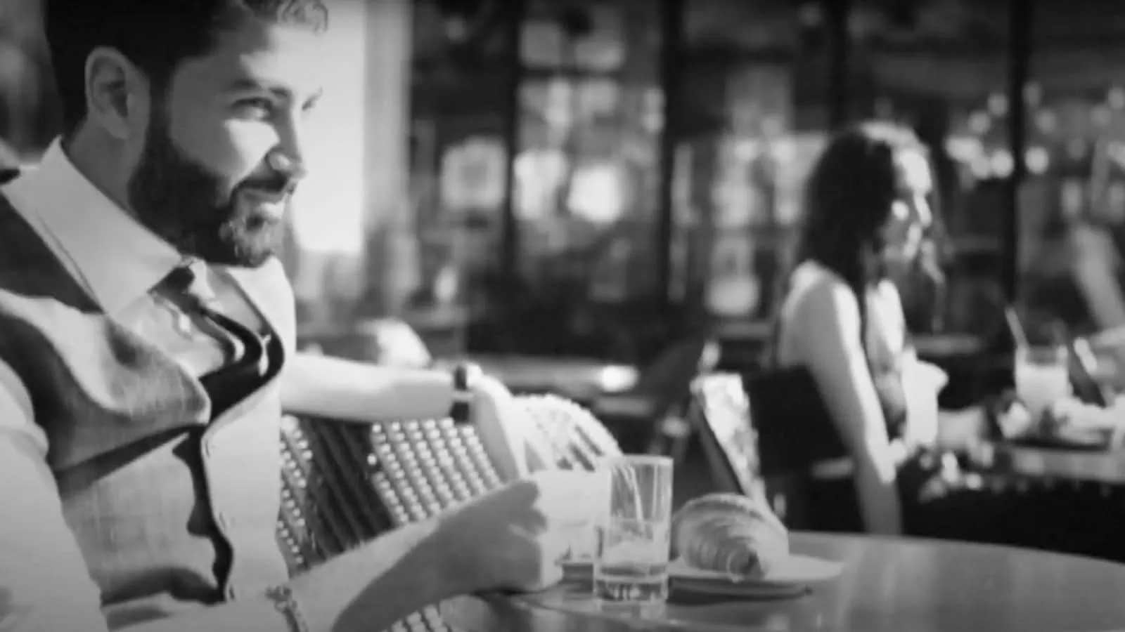 Vintage black and white photo of a couple in Charlie Chaplin-inspired attire, playfully flirting from separate tables at Cafe Carette, Trocadero, Paris, during a unique couple photoshoot.