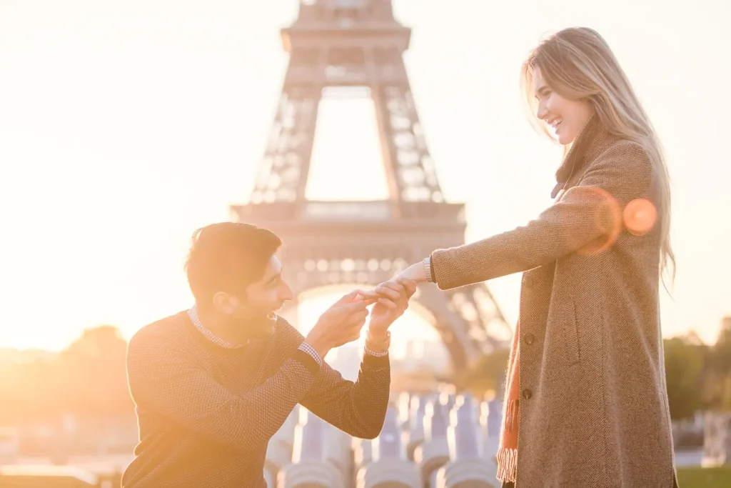 Paris engagement photographer captures groom placing ring on bride's finger at Trocadero sunrise with Eiffel Tower backdrop - professional proposal photography