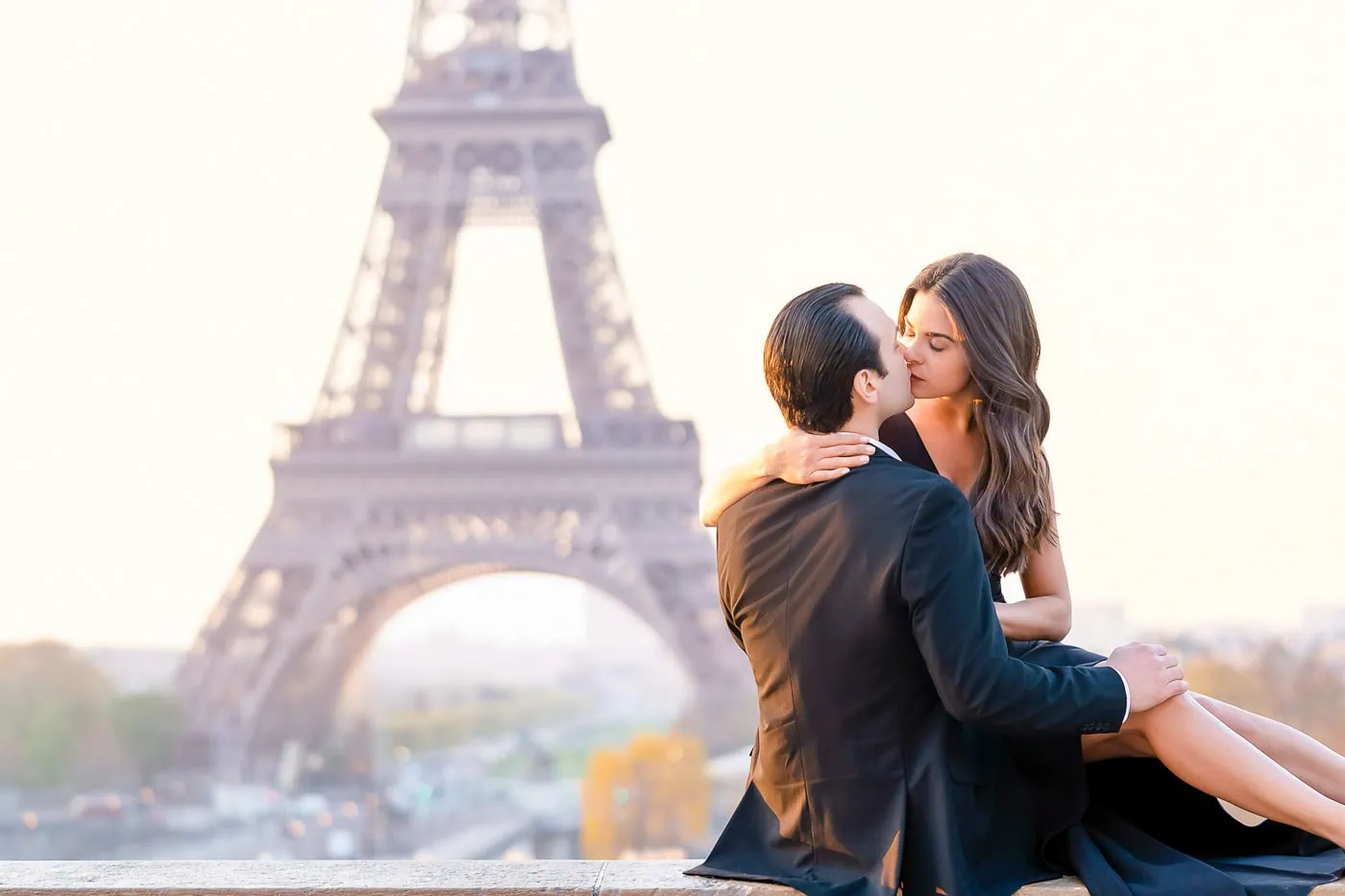 Couple kissing on the Trocadéro wall at sunrise with the Eiffel Tower in the background